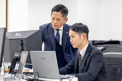 パソコンでデータを確認し合うスタッフ
