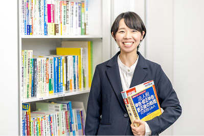 笑顔で専門書を持つ女性スタッフ