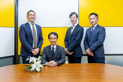 代表社員の菊水浩と、笑顔で並ぶ男性スタッフたち